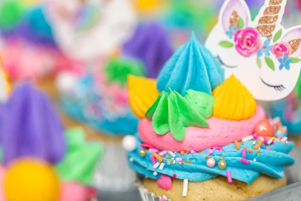 Metal tepsi üzerine çok renkli buttercream krema ile tek boynuzlu at cupcakes.