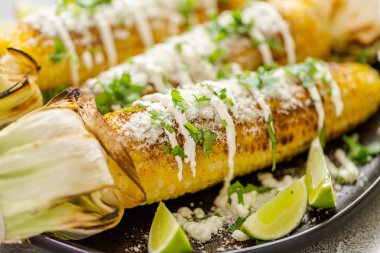 Baharat ve bir servis tabağı üzerinde taze kişniş ile süslenmiş Meksika Caddesi Mısır elote ızgara.