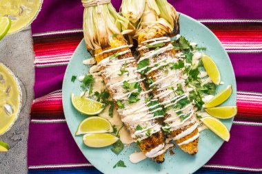 Üstten görünüm. Bir servis tabağı üzerinde baharatlar ile süslenmiş Meksika Caddesi Mısır elote ızgara.