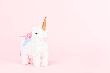 Pembe bir arka plan üzerinde beyaz tek boynuzlu at pinata.