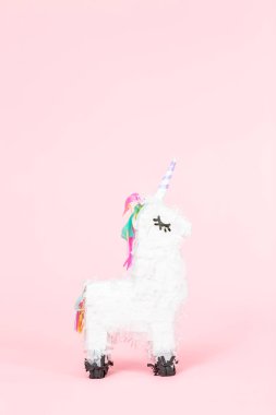 Pembe bir arka plan üzerinde beyaz tek boynuzlu at pinata.