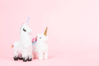 Pembe bir arka plan üzerinde beyaz tek boynuzlu at pinata.