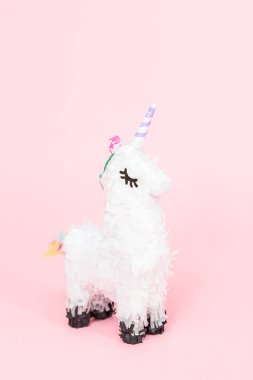 Pembe bir arka plan üzerinde beyaz tek boynuzlu at pinata.