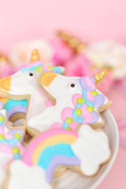 Beyaz pasta standında Kraliyet buzlanma ile dekore edilmiş tek boynuzlu at şekerli kurabiye.