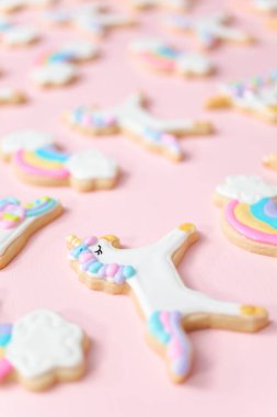 Tek boynuzlu at şekerli kurabiye pembe bir arka plan üzerine Kraliyet krema ile dekore edilmiş.