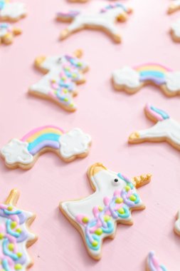 Tek boynuzlu at şekerli kurabiye pembe bir arka plan üzerine Kraliyet krema ile dekore edilmiş.