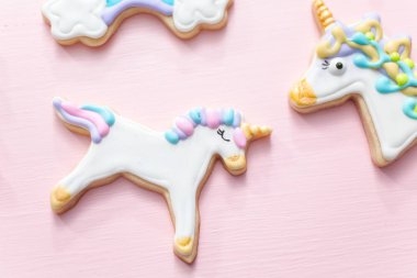 Tek boynuzlu at şekerli kurabiye pembe bir arka plan üzerine Kraliyet krema ile dekore edilmiş.