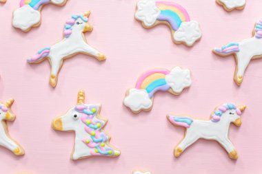 Tek boynuzlu at şekerli kurabiye pembe bir arka plan üzerine Kraliyet krema ile dekore edilmiş.