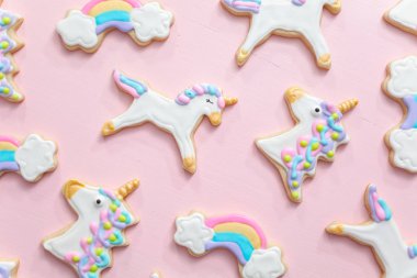 Tek boynuzlu at şekerli kurabiye pembe bir arka plan üzerine Kraliyet krema ile dekore edilmiş.