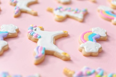 Tek boynuzlu at şekerli kurabiye pembe bir arka plan üzerine Kraliyet krema ile dekore edilmiş.