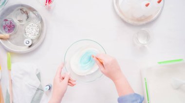 Gıda tek boynuzlu at şekerli kurabiye süslemek için Royal Icing içine boyama karıştırma.