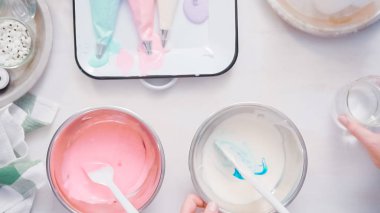 Gıda tek boynuzlu at şekerli kurabiye süslemek için Royal Icing içine boyama karıştırma.
