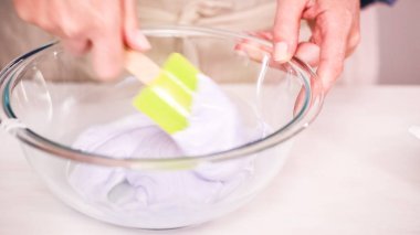 Gıda tek boynuzlu at şekerli kurabiye süslemek için Royal Icing içine boyama karıştırma.