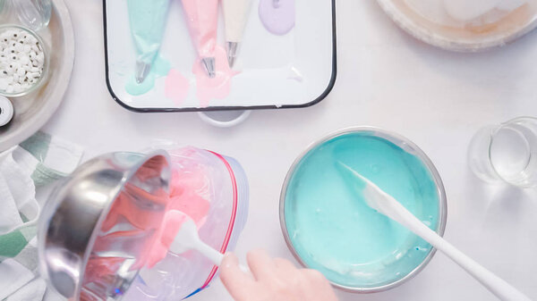 Mixing food coloring into royal icing to decorate unicorn sugar cookies.