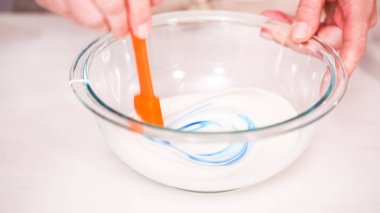 Gıda tek boynuzlu at şekerli kurabiye süslemek için Royal Icing içine boyama karıştırma.
