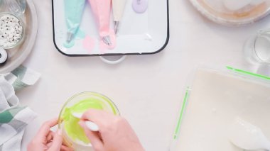Gıda tek boynuzlu at şekerli kurabiye süslemek için Royal Icing içine boyama karıştırma.