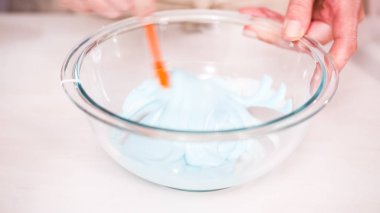 Gıda tek boynuzlu at şekerli kurabiye süslemek için Royal Icing içine boyama karıştırma.