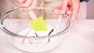 Gıda tek boynuzlu at şekerli kurabiye süslemek için Royal Icing içine boyama karıştırma.