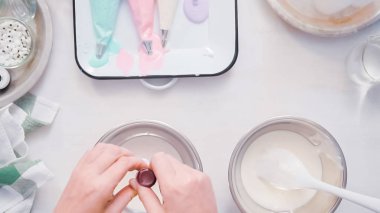 Gıda tek boynuzlu at şekerli kurabiye süslemek için Royal Icing içine boyama karıştırma.