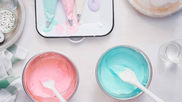 Mixing food coloring into royal icing to decorate unicorn sugar cookies.