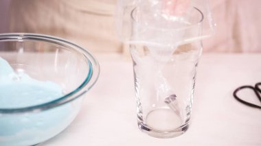 Gıda tek boynuzlu at şekerli kurabiye süslemek için Royal Icing içine boyama karıştırma.