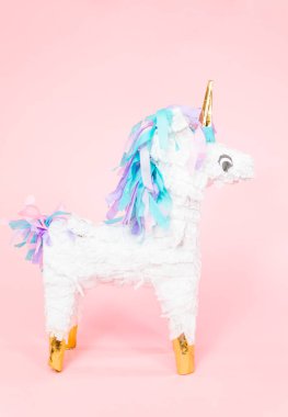 Büyük tek boynuzlu at pinata pembe bir arka plan üzerinde.