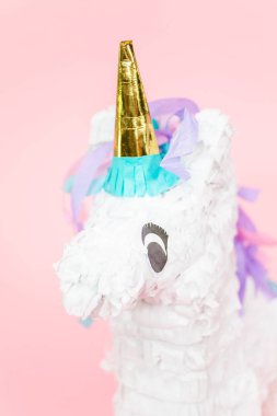 Büyük tek boynuzlu at pinata pembe bir arka plan üzerinde.