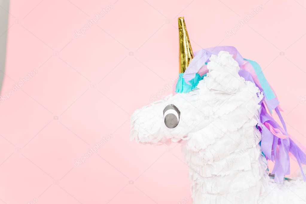 Large unicorn pinata on pink background.
