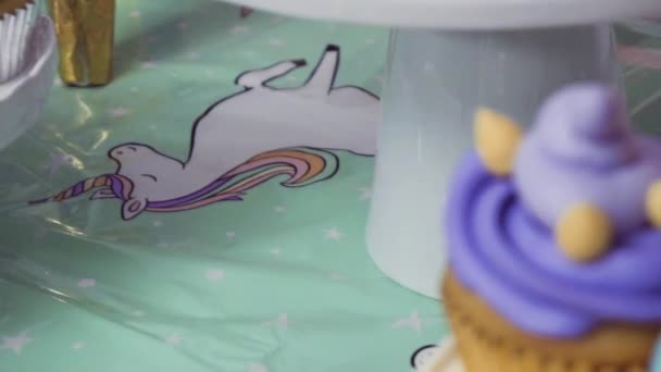 スローモーション ユニコーン ケーキ カップケーキ シュガー クッキーと小さな女の子の誕生日パーティー テーブルのクローズ アップ — ストック動画
