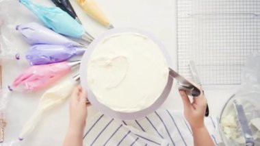 Adım adım. Üstten görünüm. Pasta Şef yığın pasta katmanları arasında tek boynuzlu at pasta oluşturmak için buzlanma buttercream ile