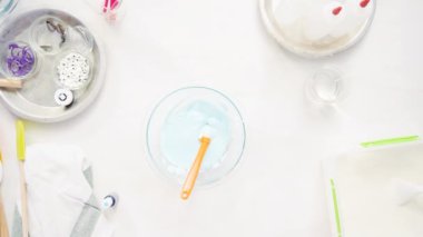 Üstten görünüm. Adım adım. Gıda tek boynuzlu at şekerli kurabiye süslemek için Royal Icing içine boyama karıştırma.
