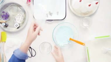 Üstten görünüm. Adım adım. Gıda tek boynuzlu at şekerli kurabiye süslemek için Royal Icing içine boyama karıştırma.