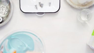 Üstten görünüm. Adım adım. Gıda tek boynuzlu at şekerli kurabiye süslemek için Royal Icing içine boyama karıştırma.