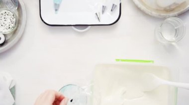 Üstten görünüm. Adım adım. Gıda tek boynuzlu at şekerli kurabiye süslemek için Royal Icing içine boyama karıştırma.