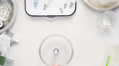 Üstten görünüm. Adım adım. Gıda tek boynuzlu at şekerli kurabiye süslemek için Royal Icing içine boyama karıştırma.
