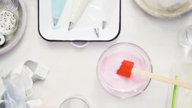 Üstten görünüm. Adım adım. Gıda tek boynuzlu at şekerli kurabiye süslemek için Royal Icing içine boyama karıştırma.