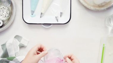Üstten görünüm. Adım adım. Gıda tek boynuzlu at şekerli kurabiye süslemek için Royal Icing içine boyama karıştırma.