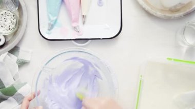 Üstten görünüm. Adım adım. Gıda tek boynuzlu at şekerli kurabiye süslemek için Royal Icing içine boyama karıştırma.