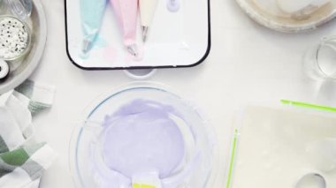 Üstten görünüm. Adım adım. Gıda tek boynuzlu at şekerli kurabiye süslemek için Royal Icing içine boyama karıştırma.