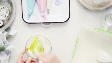 Üstten görünüm. Adım adım. Gıda tek boynuzlu at şekerli kurabiye süslemek için Royal Icing içine boyama karıştırma.