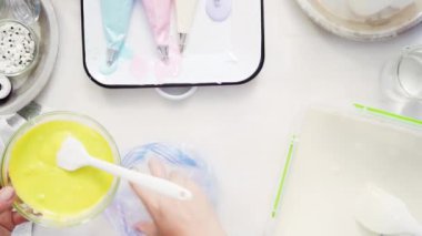 Üstten görünüm. Adım adım. Gıda tek boynuzlu at şekerli kurabiye süslemek için Royal Icing içine boyama karıştırma.