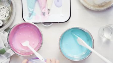 Üstten görünüm. Adım adım. Gıda tek boynuzlu at şekerli kurabiye süslemek için Royal Icing içine boyama karıştırma.