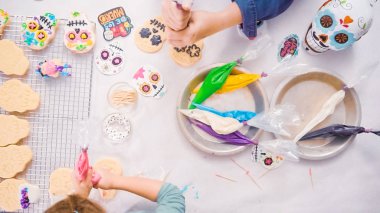Anne ve kızı şeker kafatası kurabiye Dia de los Muertos tatil için Kraliyet buzlanma ile dekorasyon üstten görünüm.