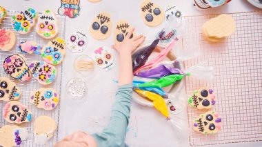 Küçük kızın Dia de los Muertos tatil için Kraliyet buzlanma ile şeker kafatası çerezleri dekorasyon havai görünümü.