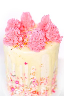 Pembe ve beyaz buttercream krem kek pembe sprinkles ve beyaz çikolata ganache damla.