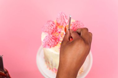 Pembe ve beyaz buttercream krem kek pembe sprinkles ve beyaz çikolata ganache damla Doğum günü mumları koyarak kadın.