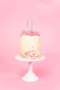 Pembe ve beyaz buttercream krem kek pembe sprinkles ve beyaz çikolata ganache damla üzerinde beş Doğum günü mumları.