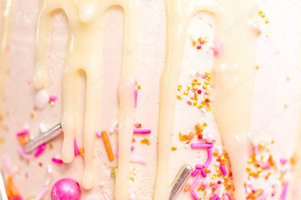 Detail of pink and white buttercream cream cake with pink sprinkles and white chocolate ganache drip.
