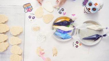 Anne ve kızı şeker kafatası kurabiye Dia de los Muertos tatil için Kraliyet buzlanma ile dekorasyon üstten görünüm.