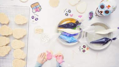 Anne ve kızı şeker kafatası kurabiye Dia de los Muertos tatil için Kraliyet buzlanma ile dekorasyon üstten görünüm.